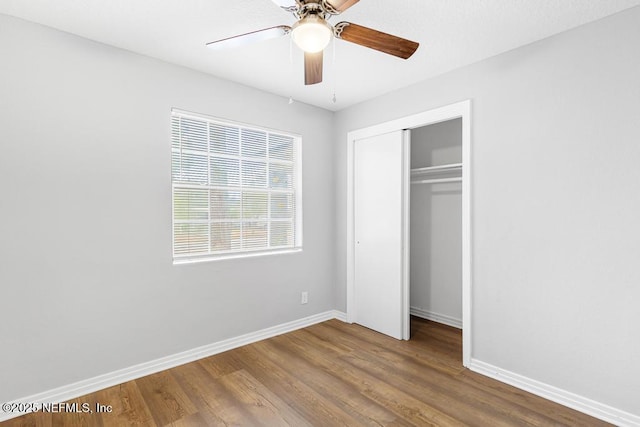 unfurnished bedroom featuring hardwood / wood-style flooring, a closet, and ceiling fan