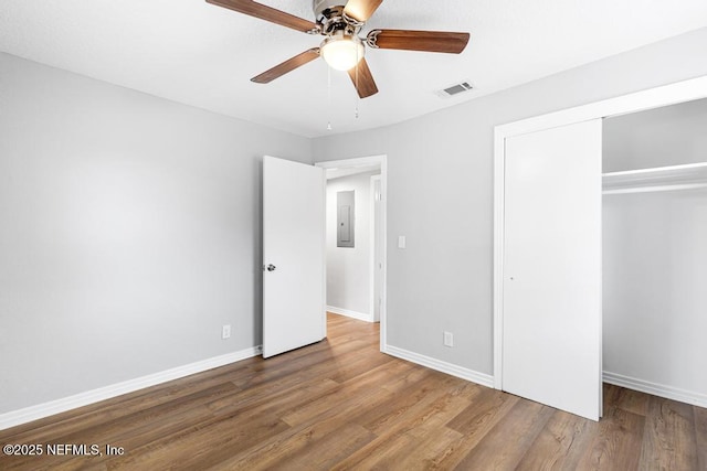 unfurnished bedroom featuring ceiling fan, hardwood / wood-style floors, electric panel, and a closet