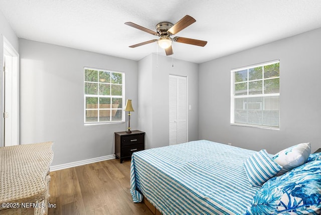 bedroom featuring multiple windows, light hardwood / wood-style flooring, a closet, and ceiling fan