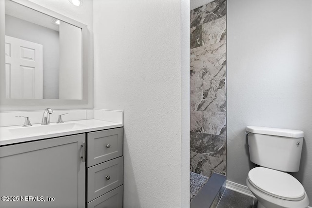 bathroom with vanity, toilet, and tiled shower