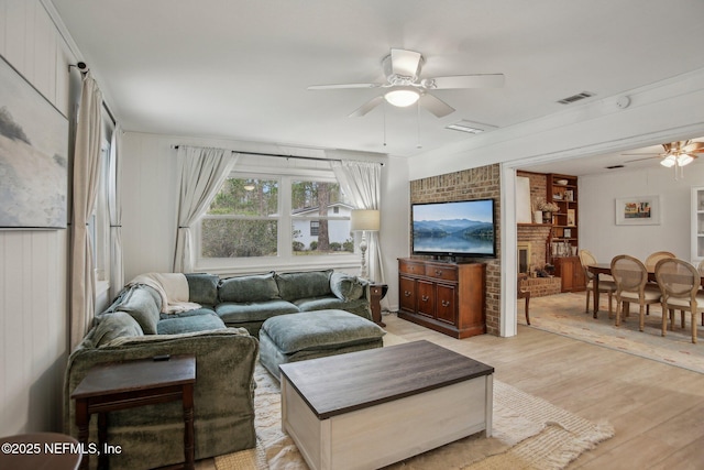 living room with ceiling fan, a fireplace, and light wood-type flooring