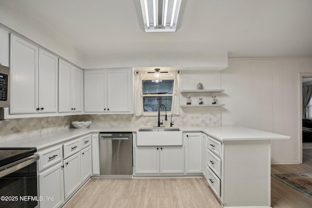 kitchen featuring sink, appliances with stainless steel finishes, kitchen peninsula, light hardwood / wood-style floors, and white cabinets