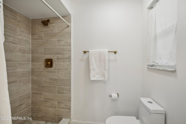 bathroom with toilet and a tile shower