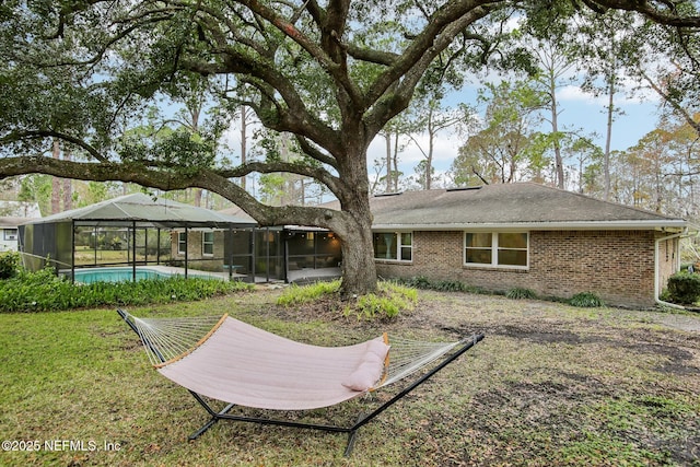 back of property with glass enclosure and a lawn