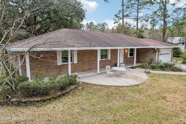 back of property with a garage, a lawn, and a patio