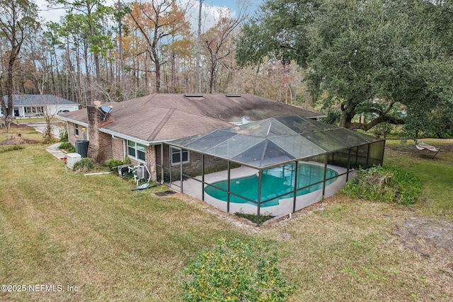 view of pool featuring a yard, a patio area, and glass enclosure