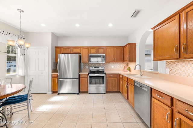 kitchen featuring stainless steel appliances, sink, pendant lighting, and backsplash