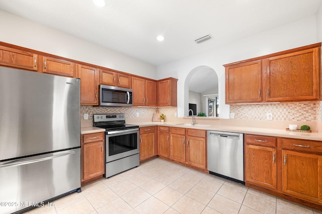 kitchen featuring sink, backsplash, stainless steel appliances, and light tile patterned floors