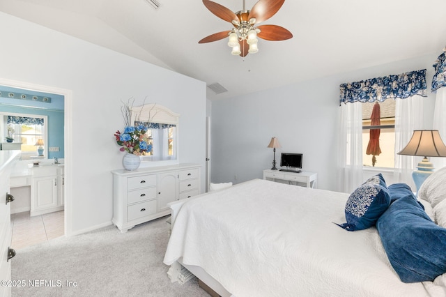 carpeted bedroom featuring ceiling fan, lofted ceiling, ensuite bathroom, and multiple windows