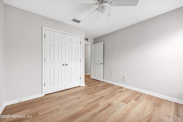 unfurnished bedroom with ceiling fan, light wood-type flooring, and a closet