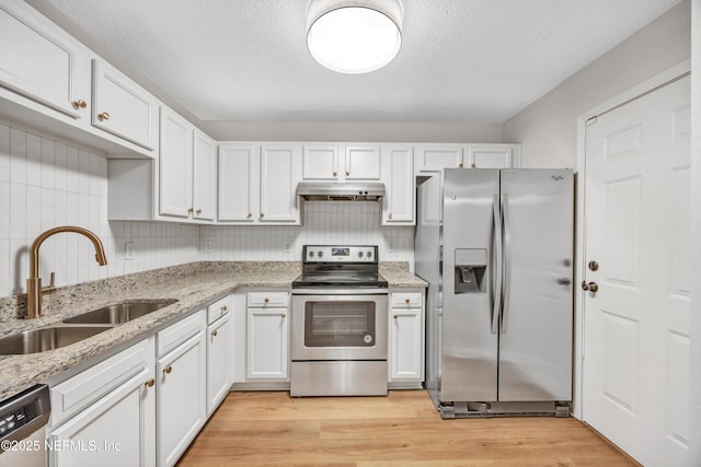 kitchen featuring sink, appliances with stainless steel finishes, white cabinetry, light stone countertops, and decorative backsplash