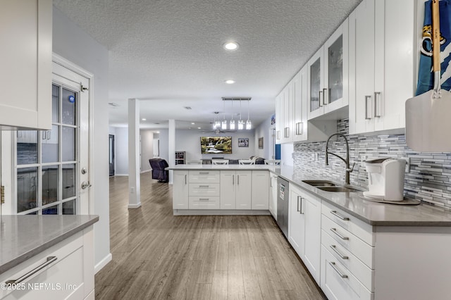 kitchen with sink, hanging light fixtures, white cabinets, stainless steel dishwasher, and kitchen peninsula