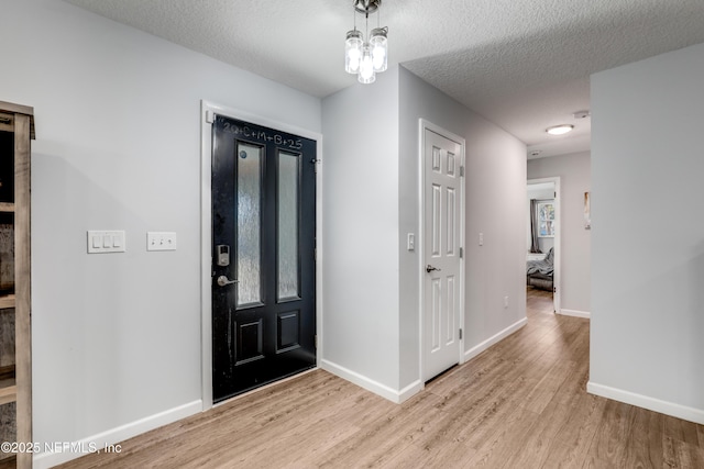 foyer with a textured ceiling and light wood-type flooring