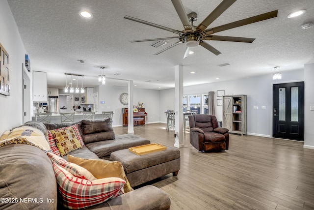 living room with hardwood / wood-style floors, a textured ceiling, and ceiling fan