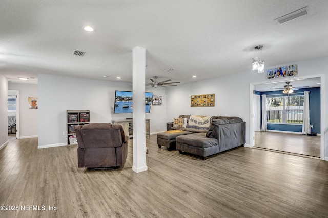 living room featuring ceiling fan, a textured ceiling, and light hardwood / wood-style flooring