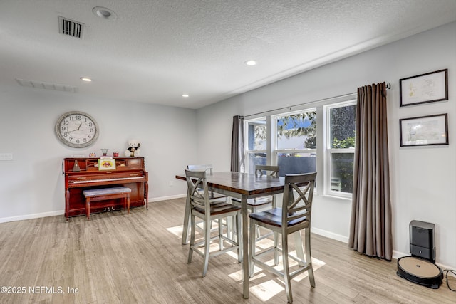 dining space featuring light hardwood / wood-style floors and a textured ceiling