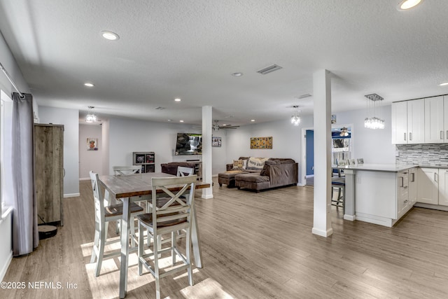 dining area featuring ceiling fan, a textured ceiling, and light wood-type flooring