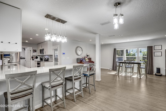 kitchen with decorative light fixtures, sink, white cabinets, and kitchen peninsula