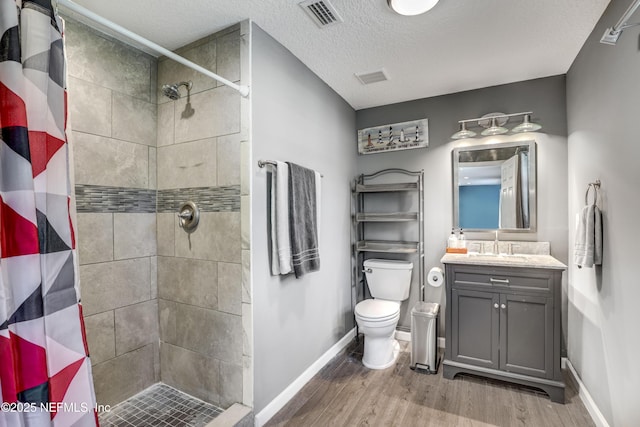 bathroom featuring hardwood / wood-style floors, vanity, toilet, a textured ceiling, and a shower with shower curtain