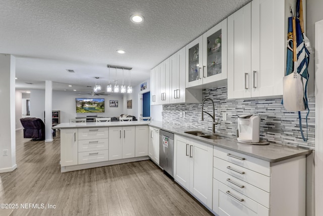 kitchen featuring sink, hanging light fixtures, stainless steel dishwasher, kitchen peninsula, and white cabinets