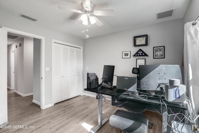 office with a textured ceiling, ceiling fan, and light wood-type flooring