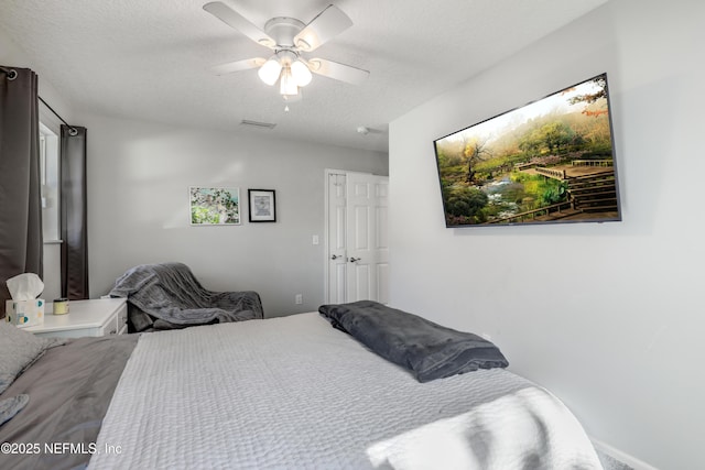 bedroom with ceiling fan and a textured ceiling