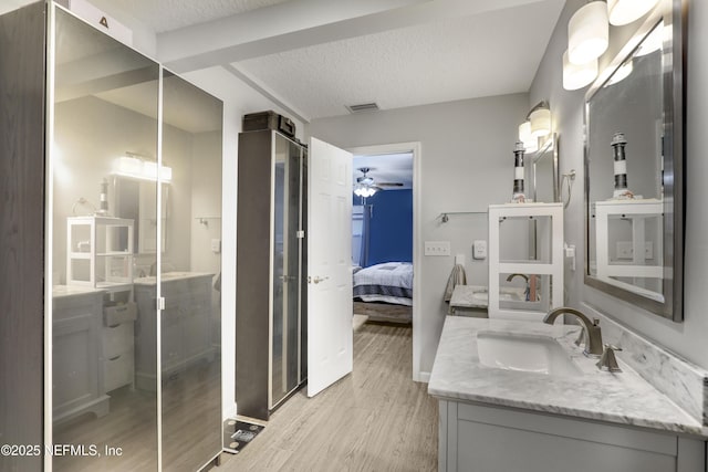 bathroom with vanity, hardwood / wood-style floors, ceiling fan, and a textured ceiling