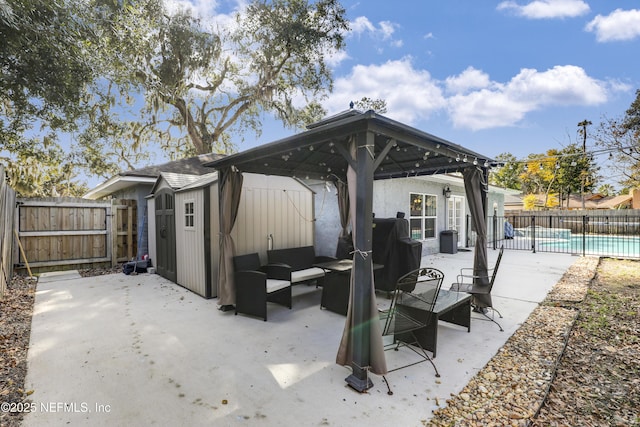 view of patio featuring a shed, a fenced in pool, a gazebo, and an outdoor living space