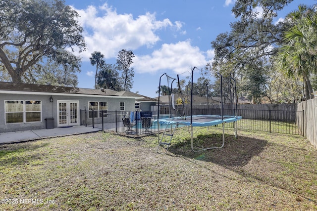 view of yard with a trampoline, a patio area, french doors, and a covered pool