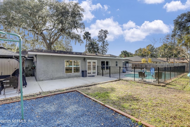 rear view of property featuring a fenced in pool, a patio area, and french doors