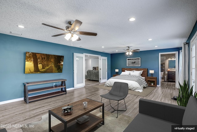 bedroom with ceiling fan, ensuite bath, light hardwood / wood-style floors, and a textured ceiling