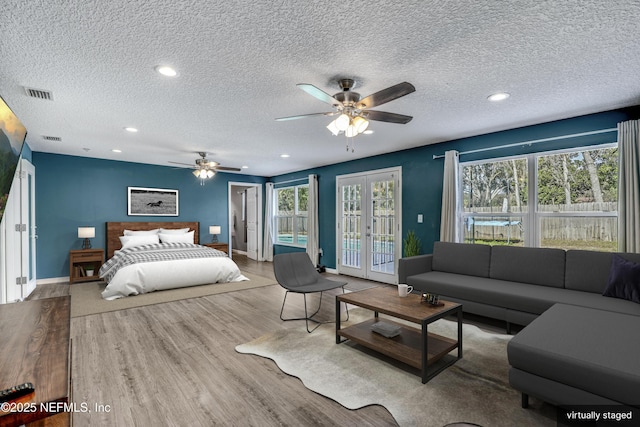 bedroom featuring light hardwood / wood-style flooring, ceiling fan, a textured ceiling, access to outside, and french doors