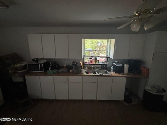 kitchen featuring ceiling fan, sink, and white cabinets