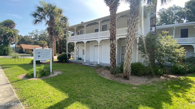 view of front of home with a balcony and a front lawn