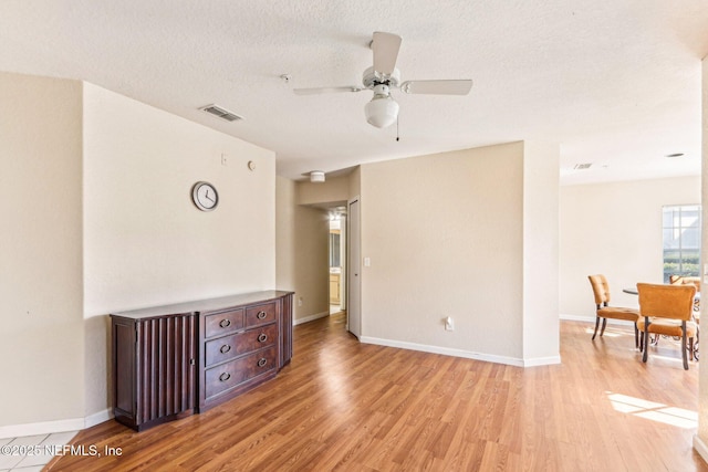 unfurnished room with ceiling fan, light hardwood / wood-style flooring, and a textured ceiling