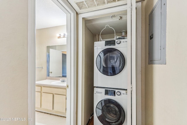 laundry room featuring stacked washer / drying machine, electric panel, and sink