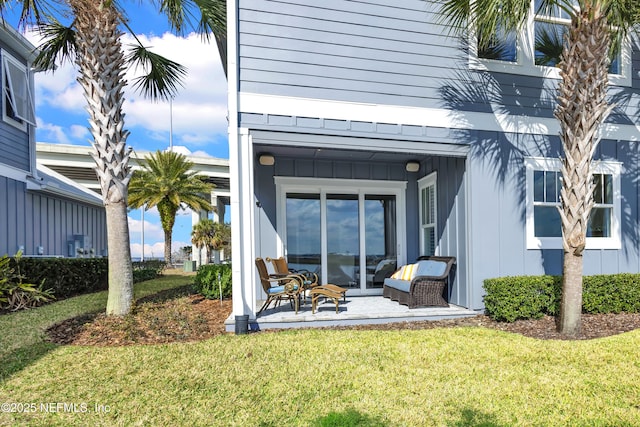 view of exterior entry with a yard and a patio