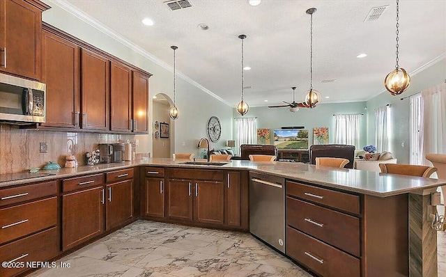 kitchen with appliances with stainless steel finishes, pendant lighting, sink, backsplash, and kitchen peninsula