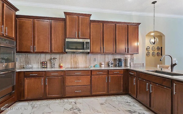 kitchen featuring sink, tasteful backsplash, ornamental molding, appliances with stainless steel finishes, and pendant lighting