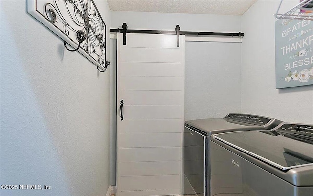 laundry room featuring independent washer and dryer, a textured ceiling, and a barn door