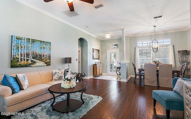 living room with ornate columns, a textured ceiling, ornamental molding, hardwood / wood-style flooring, and ceiling fan with notable chandelier