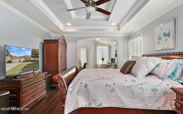 bedroom with crown molding, ceiling fan, dark hardwood / wood-style flooring, and a raised ceiling