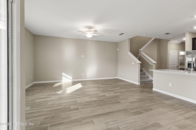 unfurnished living room with sink, a textured ceiling, and ceiling fan