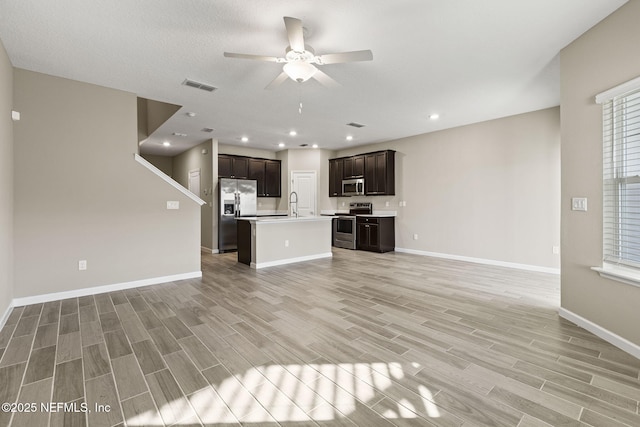 unfurnished living room featuring ceiling fan, sink, and light wood-type flooring