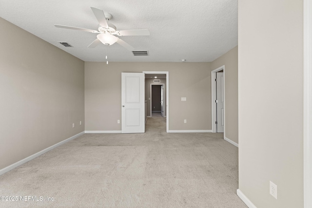 empty room featuring ceiling fan, light colored carpet, and a textured ceiling