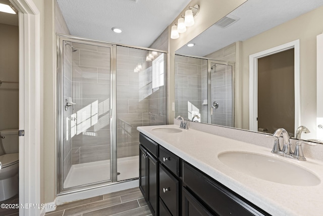 bathroom featuring vanity, a shower with shower door, and toilet