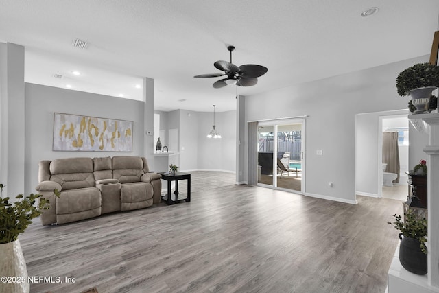 living room with ceiling fan with notable chandelier and wood-type flooring