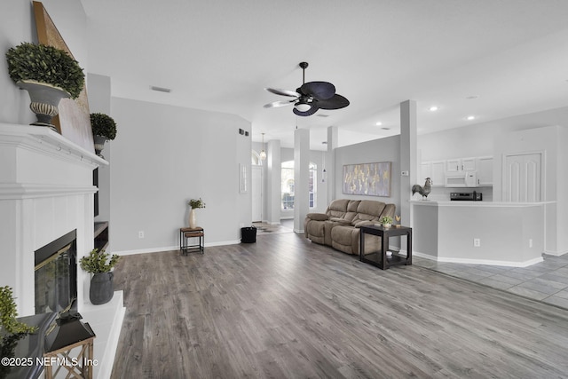 living room featuring light hardwood / wood-style floors, vaulted ceiling, and ceiling fan