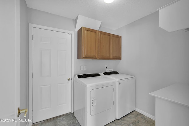 laundry area with a textured ceiling, cabinets, and separate washer and dryer