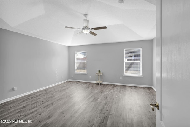 empty room with wood-type flooring, ceiling fan, a textured ceiling, and a tray ceiling